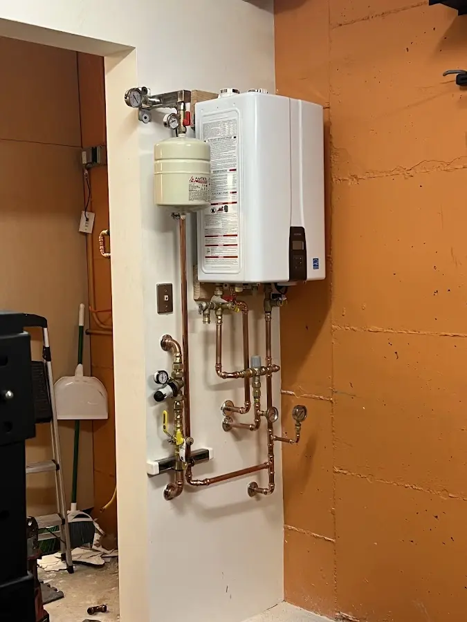 Plumbing technician inspecting water heater connections in Great Bend